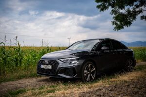 A modern Audi sedan parked in a beautiful rural setting in Slovakia under a cloudy sky.